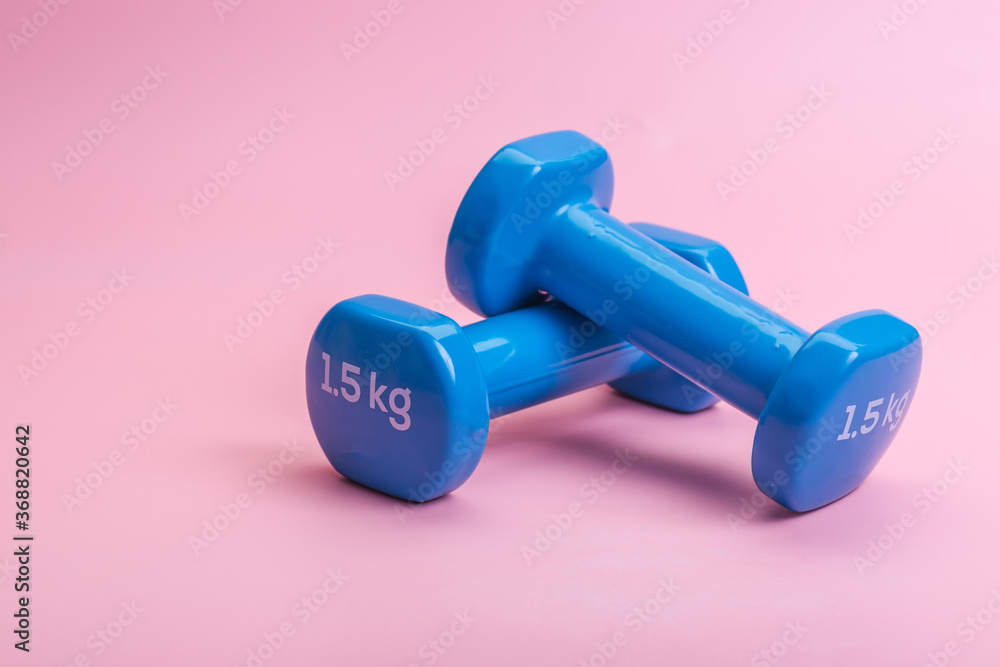 A pair of blue dumbbells on a pink background A pair of blue dumbbells on a pink background