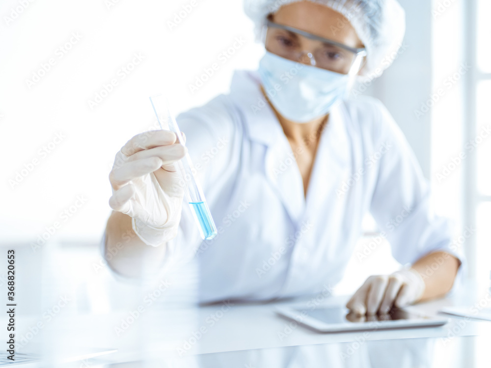 Professional female scientist in protective eyeglasses researching tube with reagents in laboratory. Concepts of medicine and science researching Professional female scientist in protective eyeglasses researching tube with reagents in laboratory. Concepts of medicine and science researching