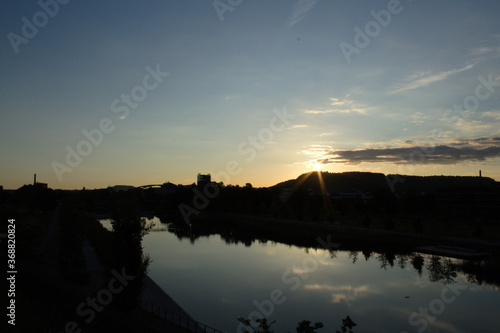 Sonnenaufgang und Sonne mit Sonnenstarahlen, Silhouette und Spiegelung im See