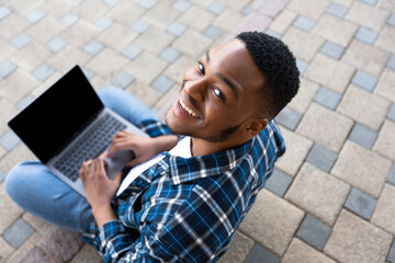 Student using laptop, sitting on the border