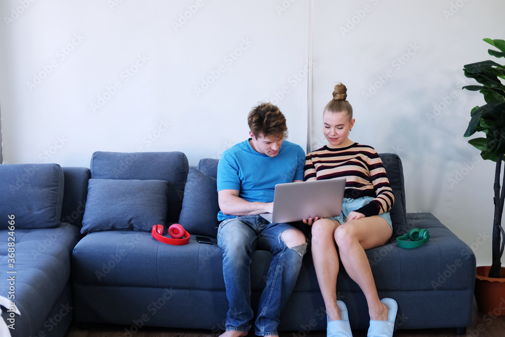 Smiling Young Caucasian couple love relaxing with laptop in social media for shopping online in living room. Technology for Married family lifestyle on holiday Concept.