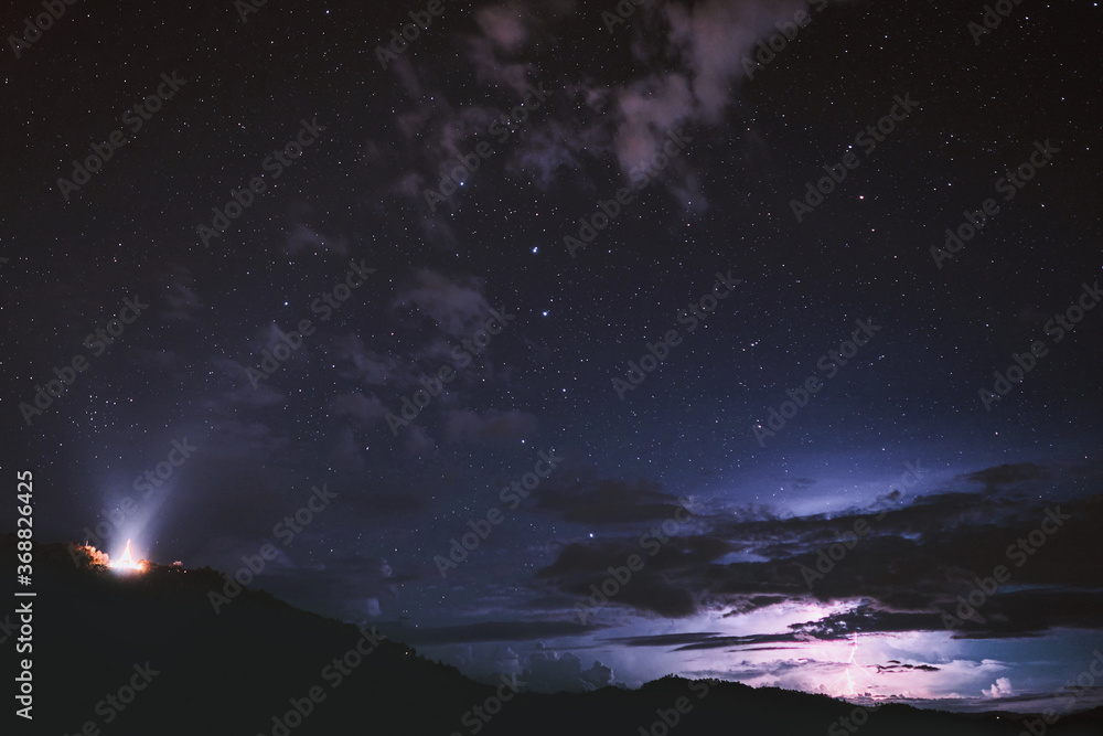 Mountain landscape showing temple against a night sky shot of the universe filled with stars in Mae Salong, Thailand