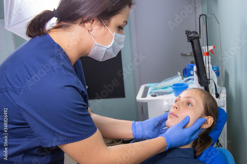 A female dentist doctor makes an inspection of a patient of a teenage girl in the clinic. 