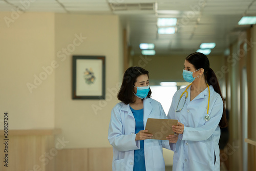 Two woman doctors  wearing mask consult while walking  at hospital