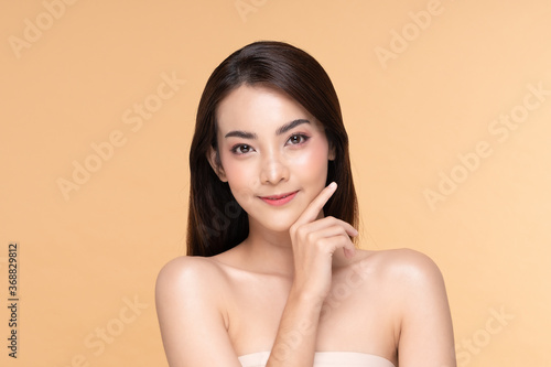Beautiful Asian young woman touching soft cheek smile with clean fresh skin Happiness and cheerful with positive emotional,isolated on Beige background,Beauty Cosmetics and Facial treatment Concept