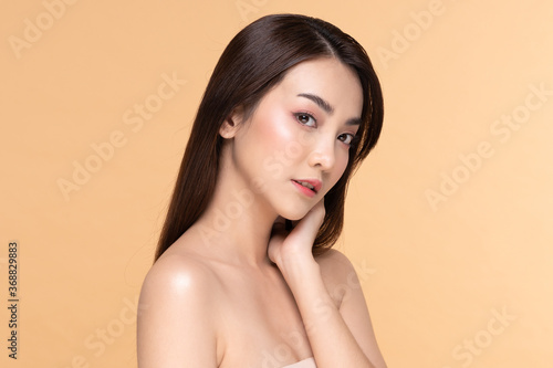 Beautiful Asian young woman touching neck smile with clean and fresh skin Happiness and cheerful with positive emotional,isolated on Beige background,Beauty and Cosmetics Concept
