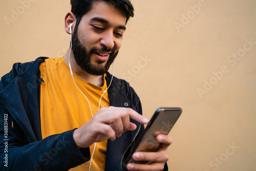 Latin man using his mobile phone with earphones.