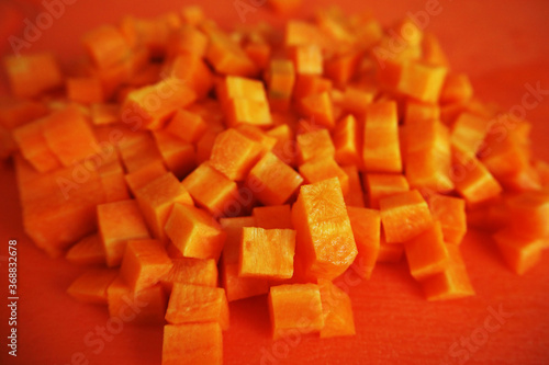 raw orange diced carrots on a plastic orange Board. stage cooking vegetables