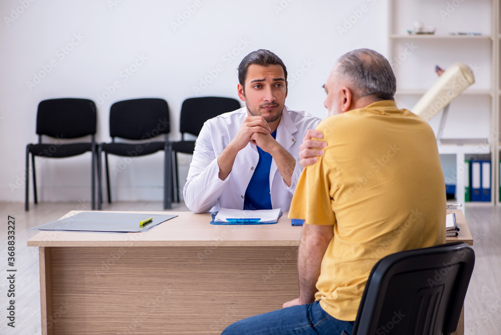 Fototapeta premium Old patient visiting young male doctor