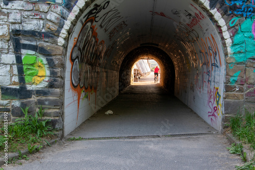 Eine Unterführung, Tunnel für Fußgänger und Fahrradfahrer.Die Bruchsteinmauer ist mit Graffiti bemalt.