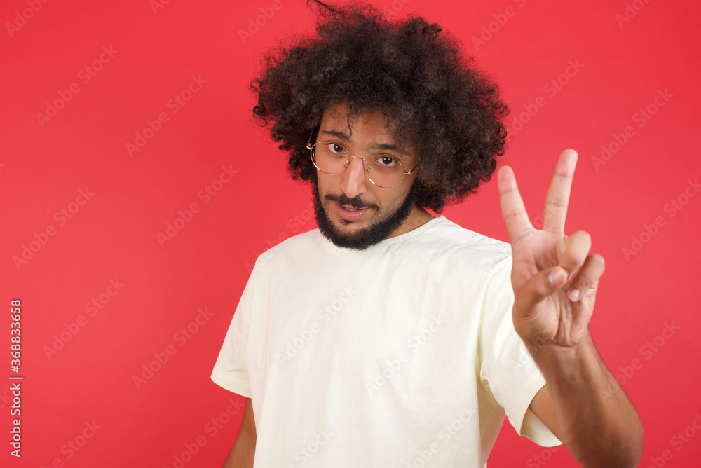 Young caucasian man standing against gray wall showing and pointing up with fingers number two while smiling confident and happy. Young caucasian man standing against gray wall showing and pointing up with fingers number two while smiling confident and happy.