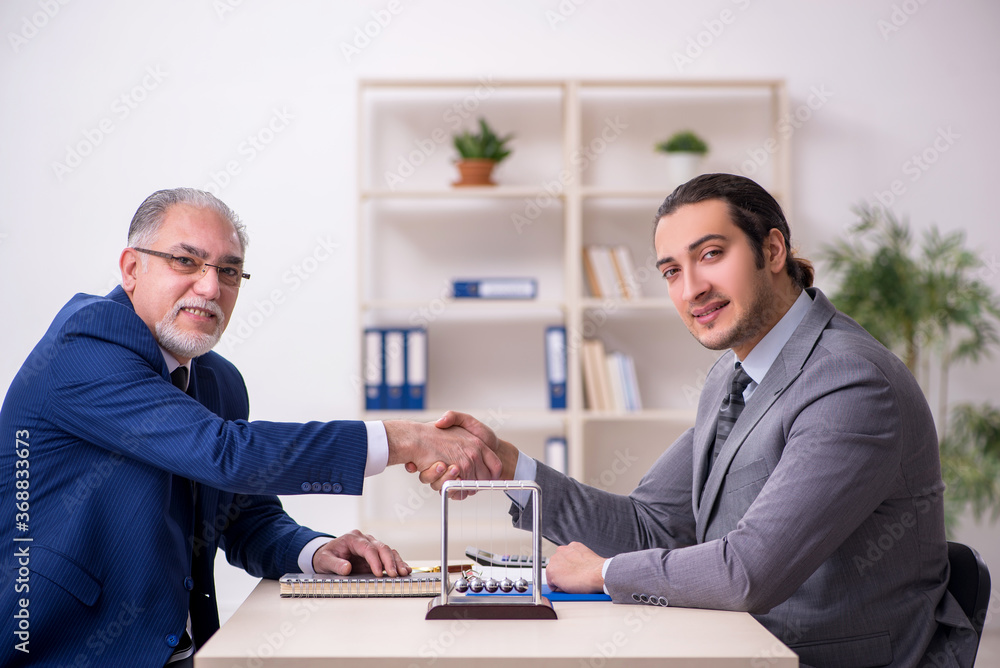 Two businessmen and meditation balls on the table Two businessmen and meditation balls on the table