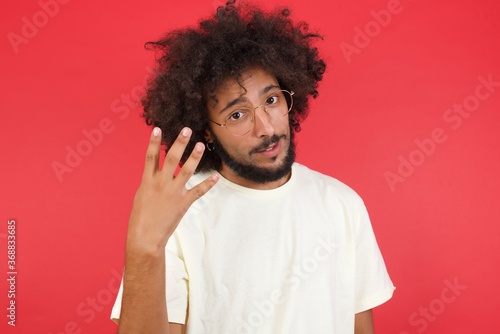 Foto Young man standing against gray wall showing and pointing up with fingers number four while smiling confident and happy