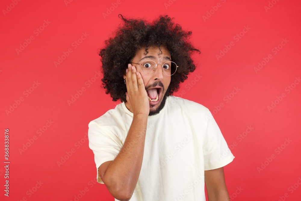 Amazement - man excited looking to the side hand on face. Surprised happy young man looking sideways in excitement. Caucasian male model on gray background. Amazement - man excited looking to the side hand on face. Surprised happy young man looking sideways in excitement. Caucasian male model on gray background.