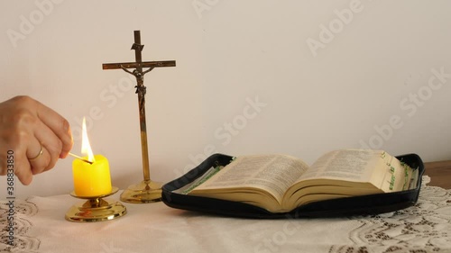 the faithful light a candle before prayer, the bible and cross photo