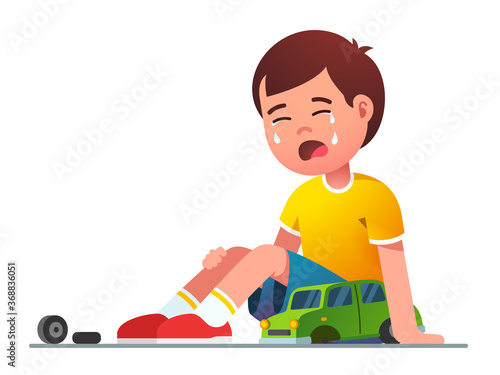 Sad boy kid sitting crying over broken toy car