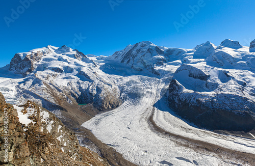 Stunning panorama view of the Gorner Glacier and Monte Rosa massif, Lyssskamm peak on Swiss Italian border from Gornergrat station on sunny autumn day with snow and blue sky, Valais, Switzerland
