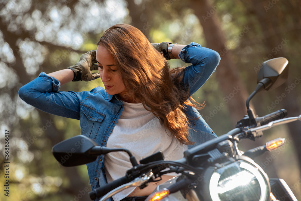 A cheerful young woman with loose, brown hair on a big bike.