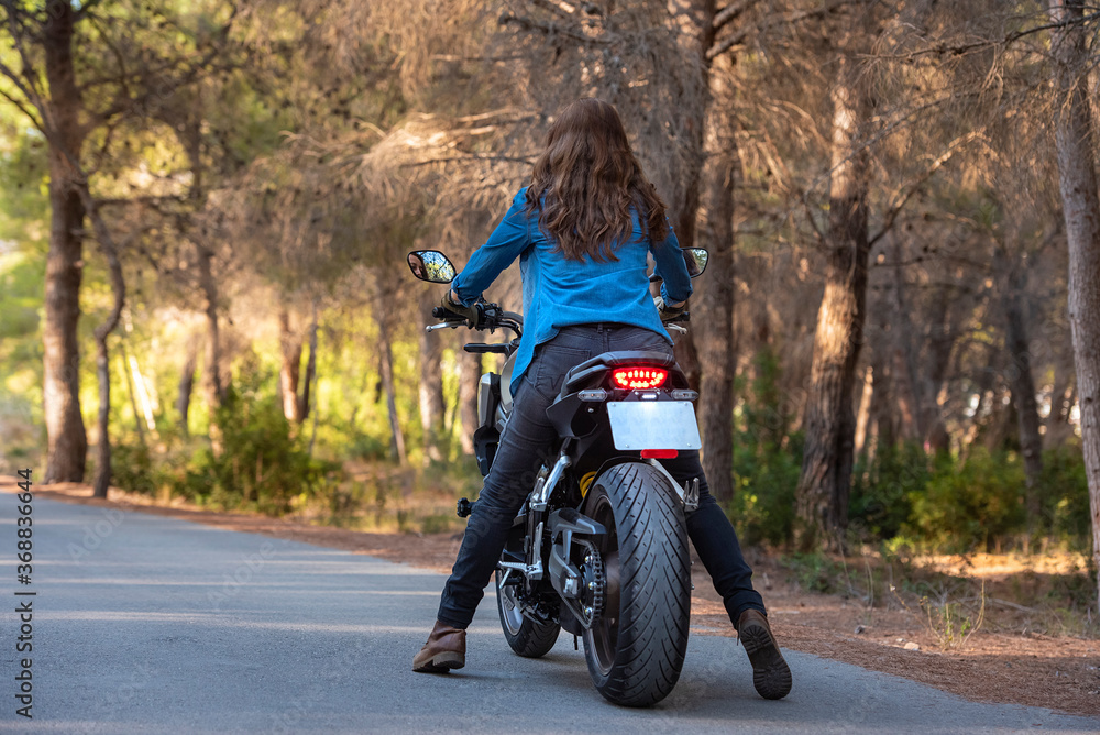 Obraz premium A cheerful young woman with loose, brown hair on a big bike.
