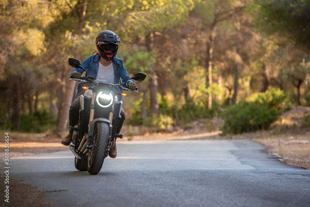 Young girl with brown hair, on a large motorbike, with a helmet on.