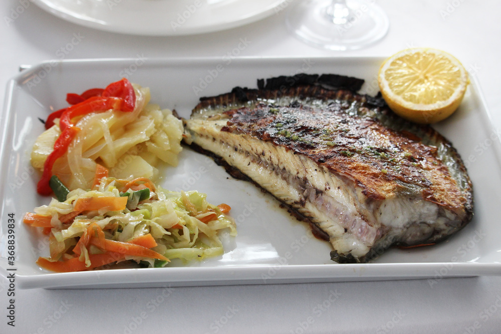 Grilled turbot with vegetable garnish and a lemon slice Grilled turbot with vegetable garnish and a lemon slice