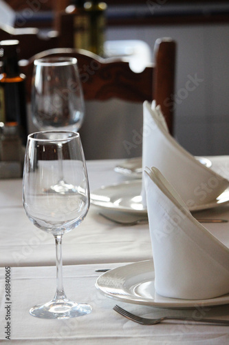 Table set in a restaurant with silverware, wine glasses and napkins