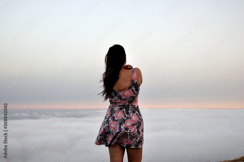 Mujer de espaldas mirando hacia mar de nubes Mujer de espaldas mirando hacia mar de nubes