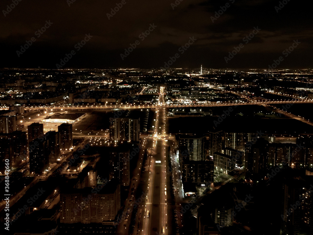 Drone overlooking the city at night, lit streets and dark sky