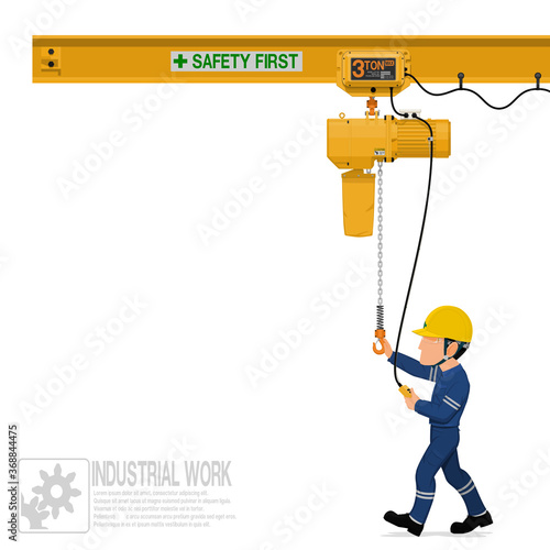 An industrial worker is operating electric chain hoist