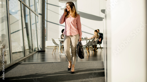 Businesswoman on cell phone walking in the office