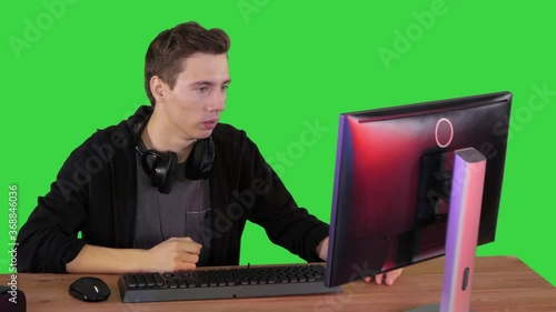 Nervous man watching video games on a PC computer on a Green Screen, Chroma Key. photo