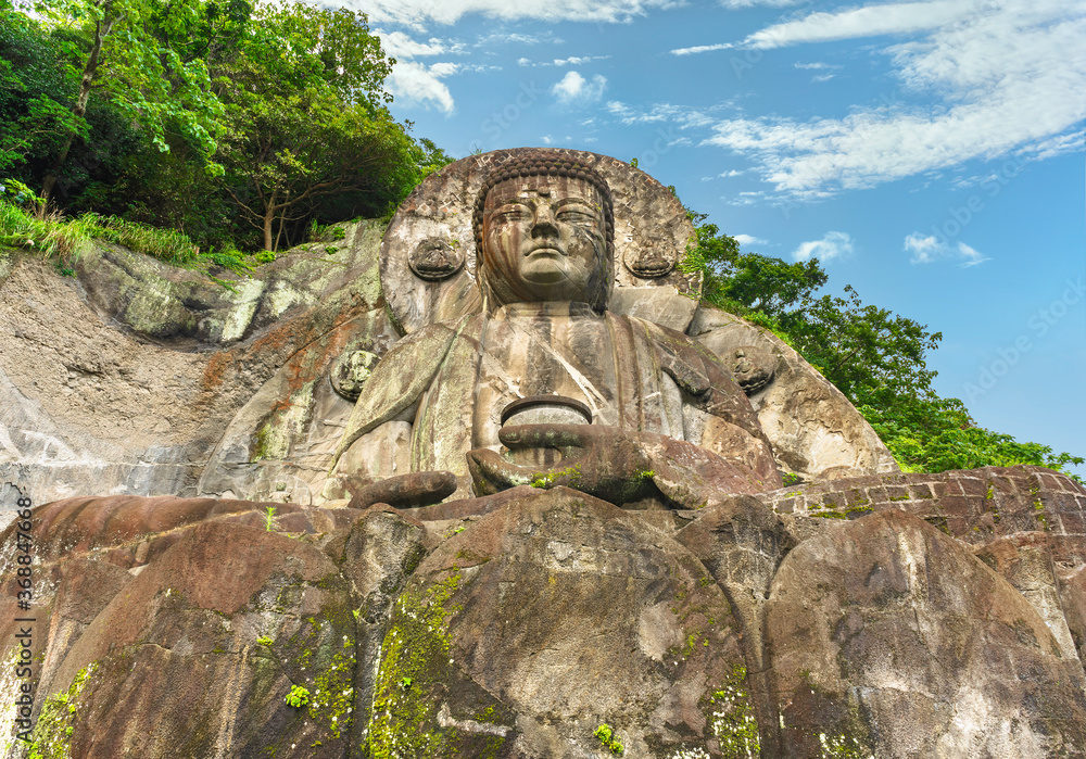 Low angle view of the largest stone-carved magaibutsu statue of giant buddha Daibutsu Yakushi of Nihonji temple on the mountain sides of Mount Nokogiri stone quarry.
