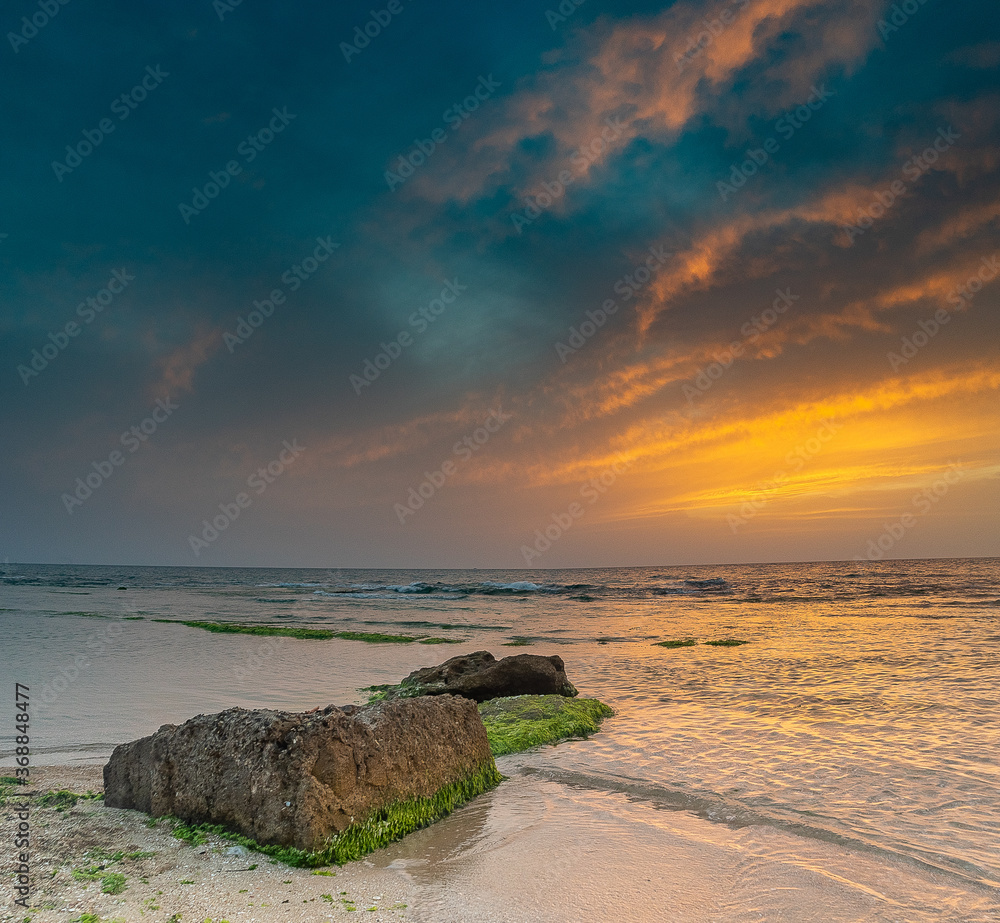 Colorful sunset with cliffs in the water on sea beach Colorful sunset with cliffs in the water on sea beach