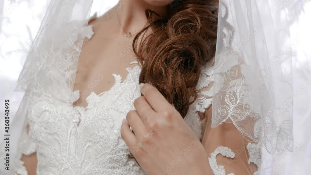 A girl in a white dress gently strokes her hair. Gathering the bride. Close-up