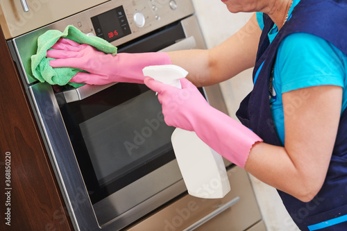 Cleaning service. Woman cleaning built-in kitchen appliances.