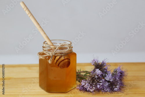 Foto A jar with honey and a wooden spoon stands on a wooden table