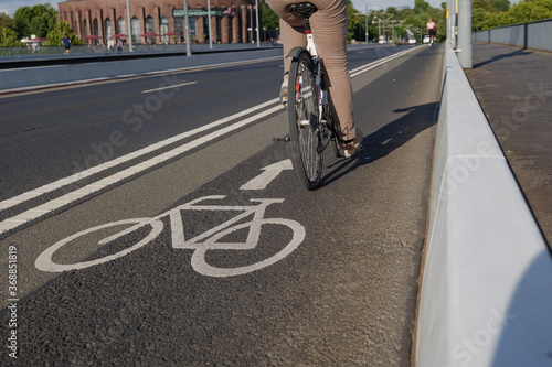 Selected focus view at white bicycle icon symbol and people ride bicycle on bicycle lane beside road on the bridge cross Rhine River in Düsseldorf, Germany. Cycling friendly city concept in Europe. 