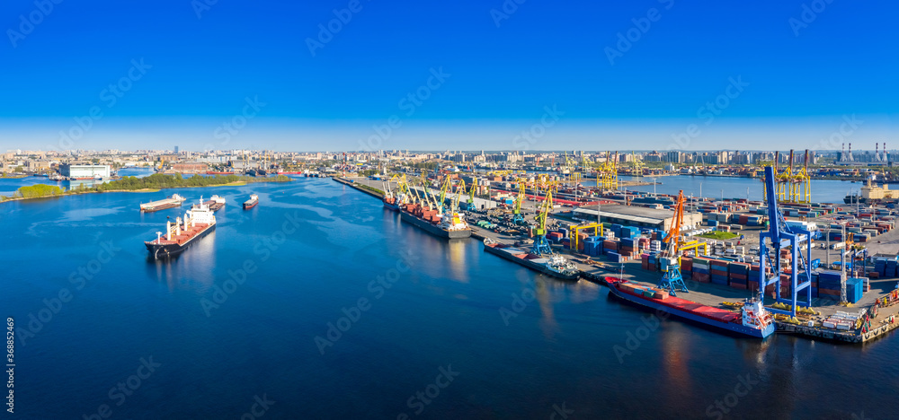Commercial sea port from a drone. View from the height to the ships and the port.  Container ships in import and export. Loading of vessels in the port. International cargo transportation.