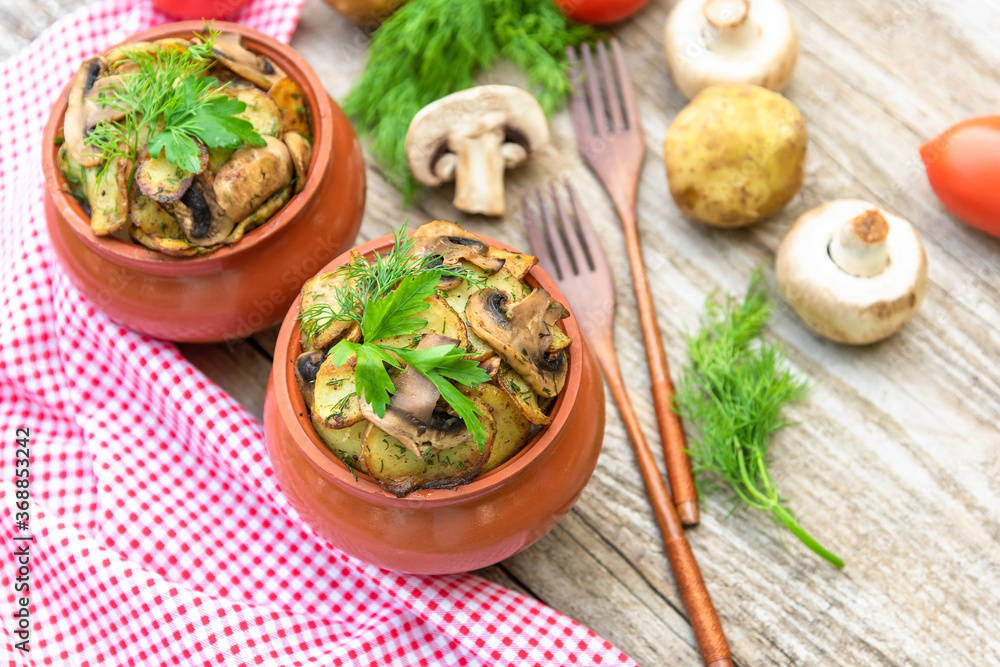 Baked potatoes with chicken and mushrooms with the addition of different seasonings. in clay pots.