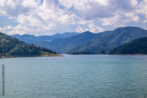 Zaovine lake with beautiful blue water on Tara national park in Serbia, Europe. Landscape with a cloudy sky, and mountains. Tourism and travel concept © Emilija