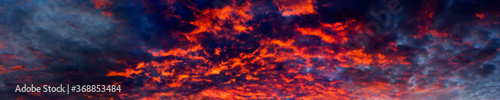 Blazing sky, dramatic sunset. Sky is like a conflagration, majestic atmosphere. Clouds at sunset illuminated by the sun from below, panoramic view, big size