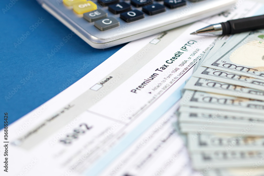 Blank tax form 8962 premium, pen, dollar bills, calculator. Concept of business and taxation. Selective focus Blank tax form 8962 premium, pen, dollar bills, calculator. Concept of business and taxation. Selective focus