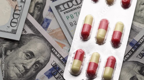 Pills rotating on money - healthcare cost concept. Close-up