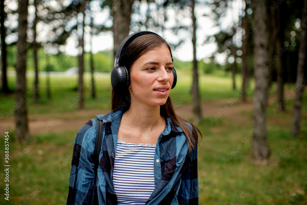 Fototapeta premium Portrait of young woman listening music outdoors 