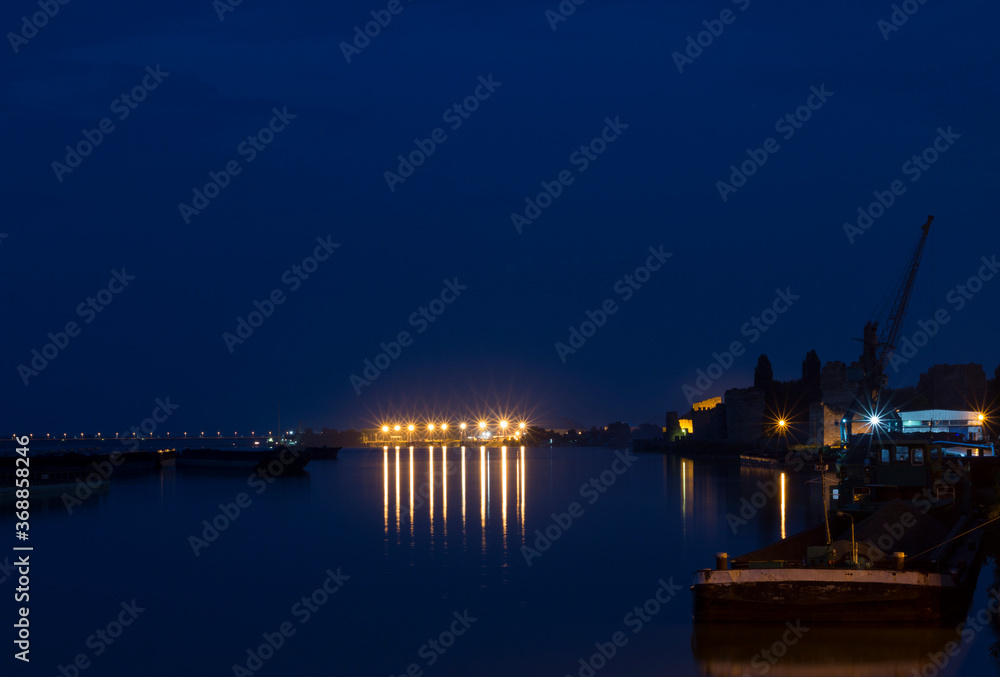 Night view on river port with cargo ships and crane during blue hour