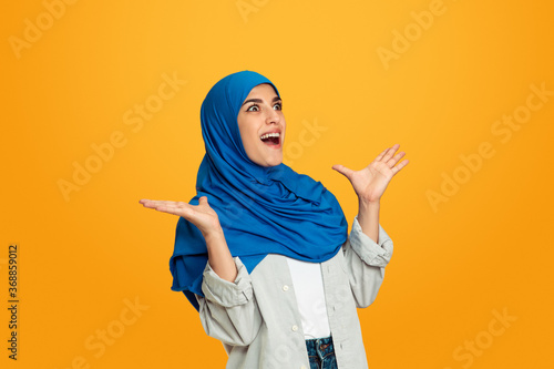 Surprising. Young muslim woman isolated on yellow studio background. Stylish, trendy and beautiful female model. Human emotions, facial expression, sales, ad, shopping concept. Copyspace.