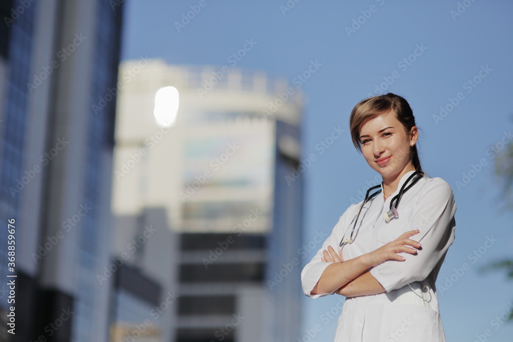 Portrait of a beautiful female doctor or nurse. Skyscraper, sky. Health concept.