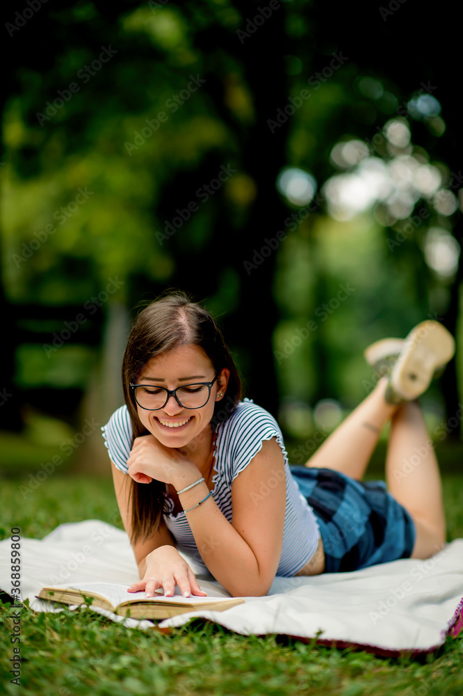 Caucasian beautiful young woman lying on a meadow, reading a book Caucasian beautiful young woman lying on a meadow, reading a book