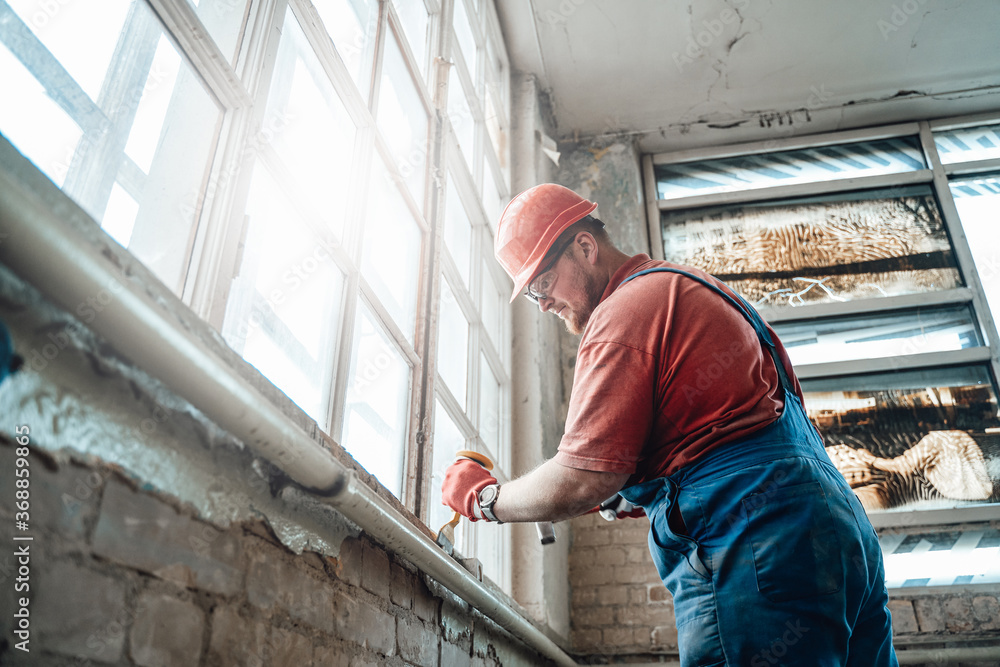 Concentrated and highly skilled worker handling a windowsill on a large construction site Concentrated and highly skilled worker handling a windowsill on a large construction site