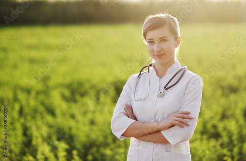 Portrait of a beautiful female doctor or nurse on green grass background